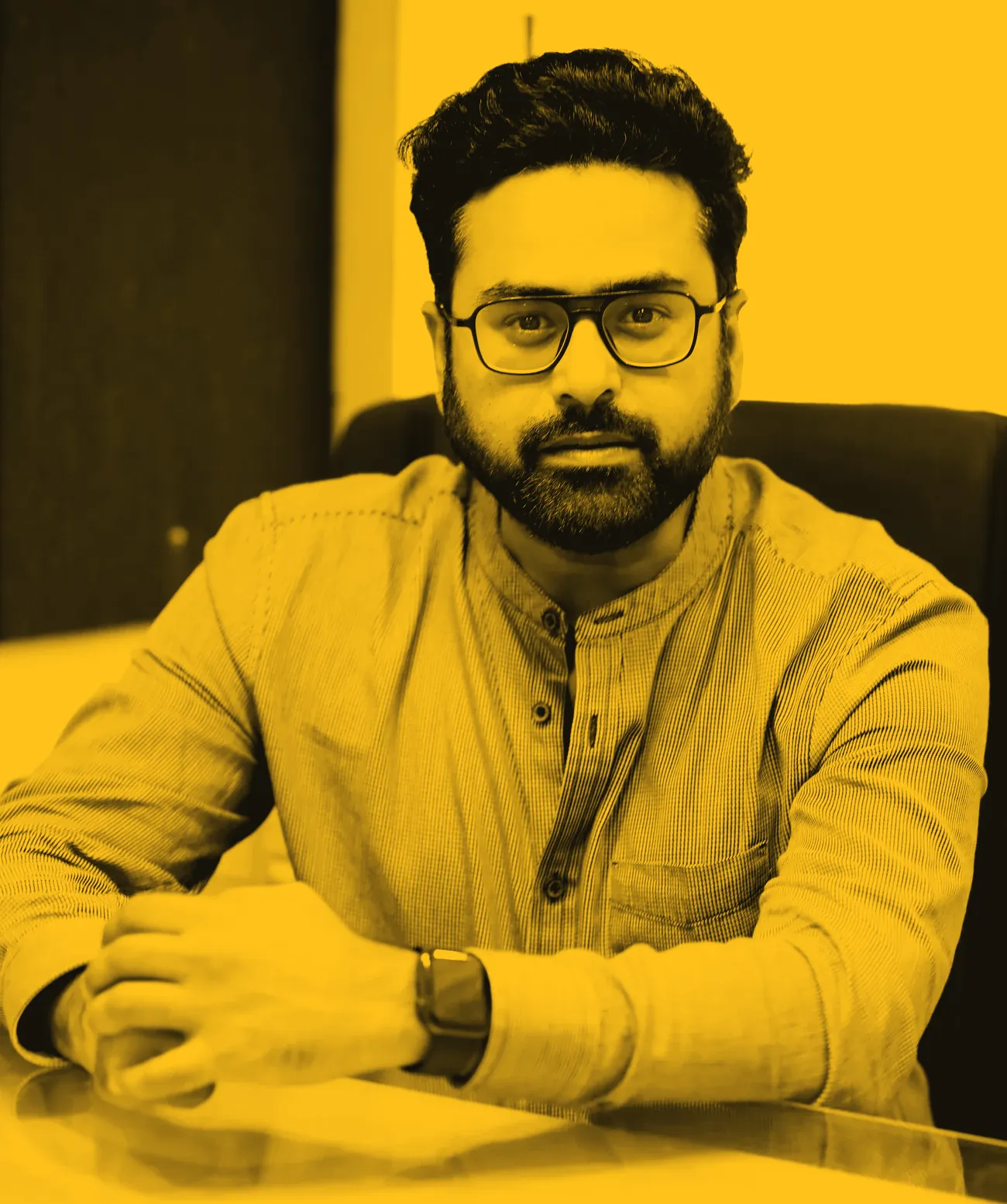Black and white portrait of Dinesh Sajnani at a desk